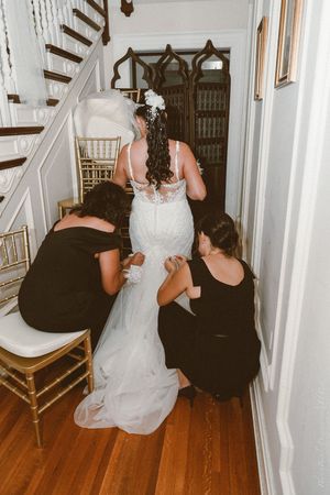 Three women cropped from shoulders down in black and white dresses on hardwood floor.