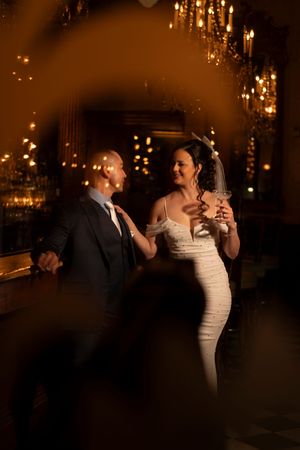 A romantic couple dancing together under warm glowing lights during their wedding reception.