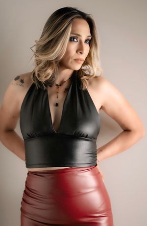 Model wearing black halter top and red leather skirt in studio portrait.
