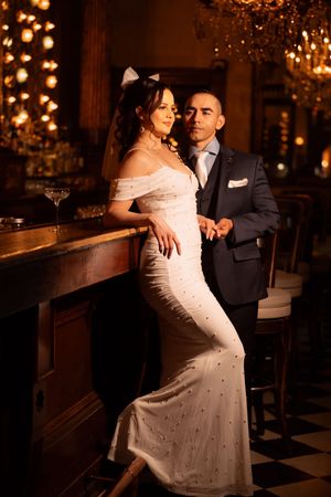 A couple shares an intimate dance together in a dimly lit venue with sparkling lights in the background.