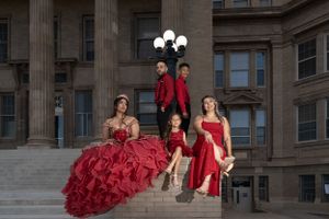 Group in matching red formal attire posing on grand stone steps for glamorous portrait.