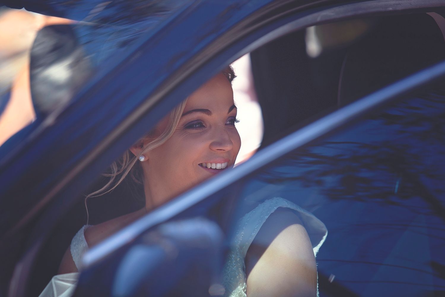 Smiling bride seen through a car window on her wedding day.