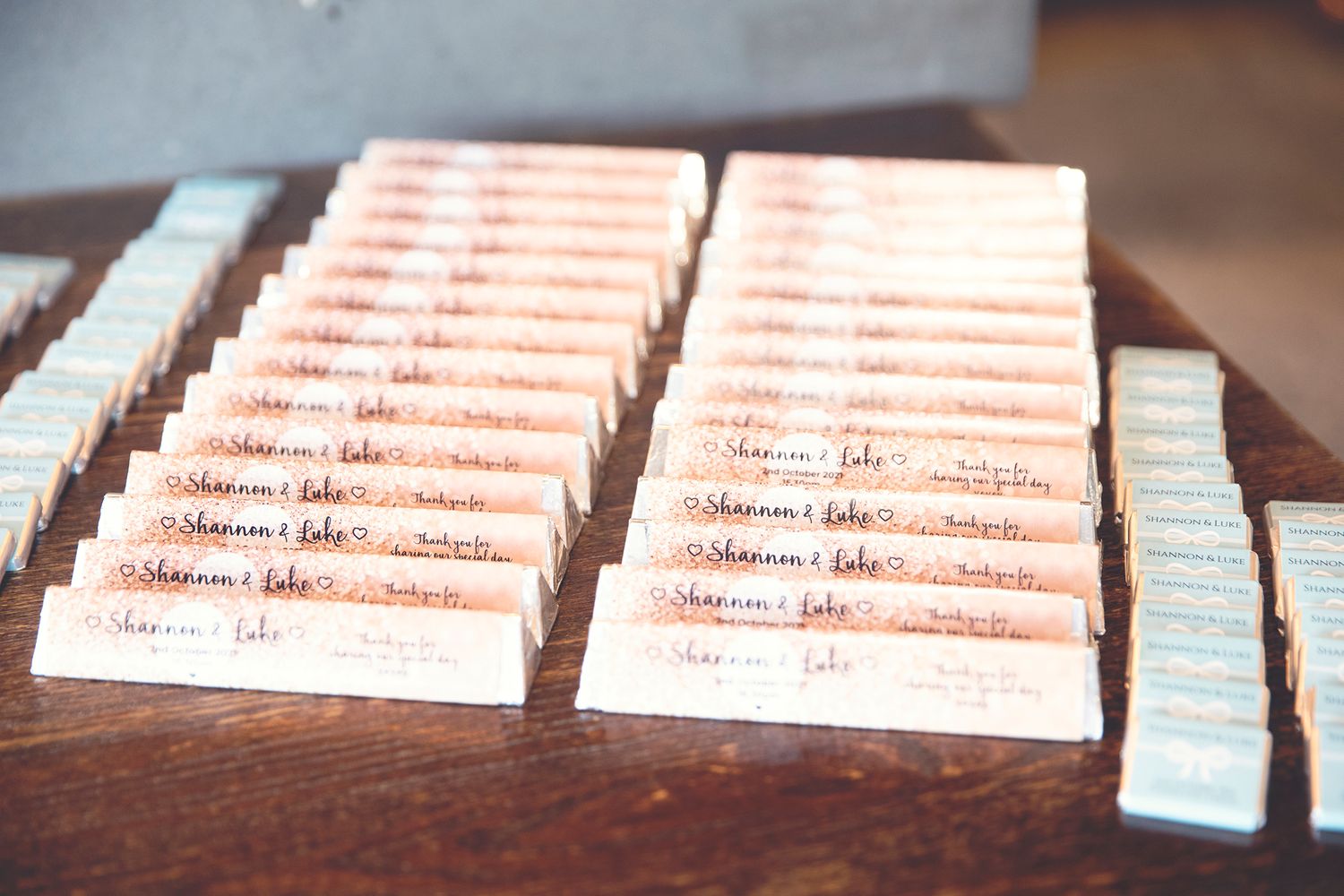 Rows of handwritten wedding escort cards displayed on a rustic wooden table.
