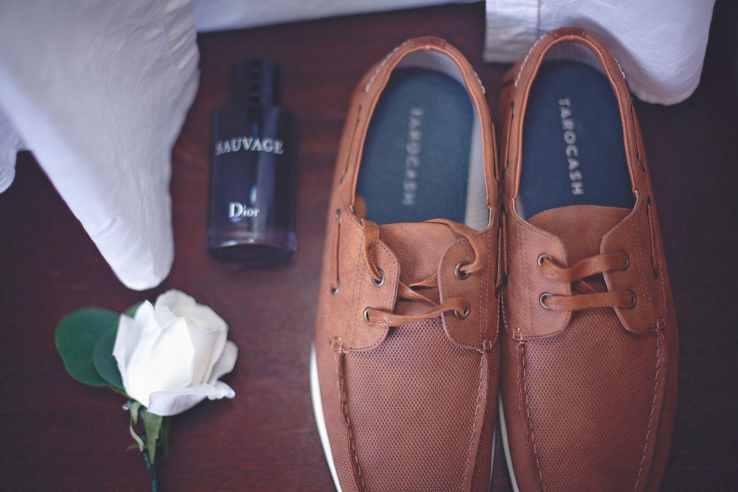 Brown leather boat shoes with Dior Sauvage cologne and white rose boutonniere.