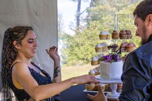 Wedding guests enjoying a dessert table with cupcakes and treats at an outdoor reception celebration.