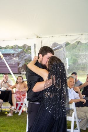 A romantic first dance moment under a white tent during an outdoor wedding reception.