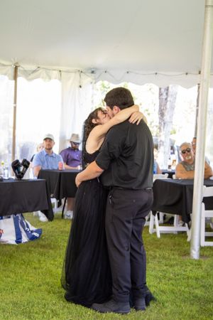 Couples dancing together under a white tent at an outdoor event with grass and tables visible.