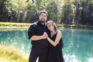 A couple poses together against a scenic turquoise lake backdrop.