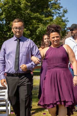 Wedding party poses together in coordinated purple and black formal attire.