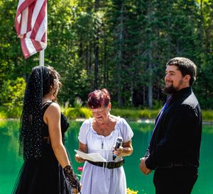 A wedding ceremony in progress with an American flag and forest backdrop.