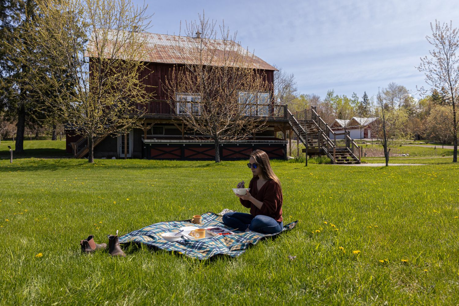 Person enjoying a picnic on a blanket in front of a rustic house.