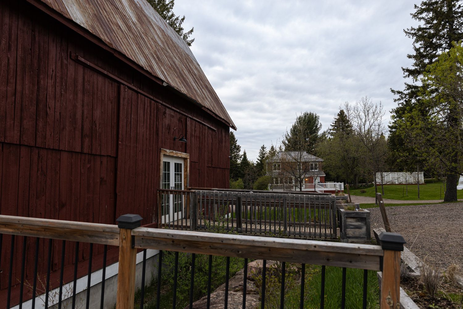 Historic red barn building with white windows and wooden railing against cloudy sky.