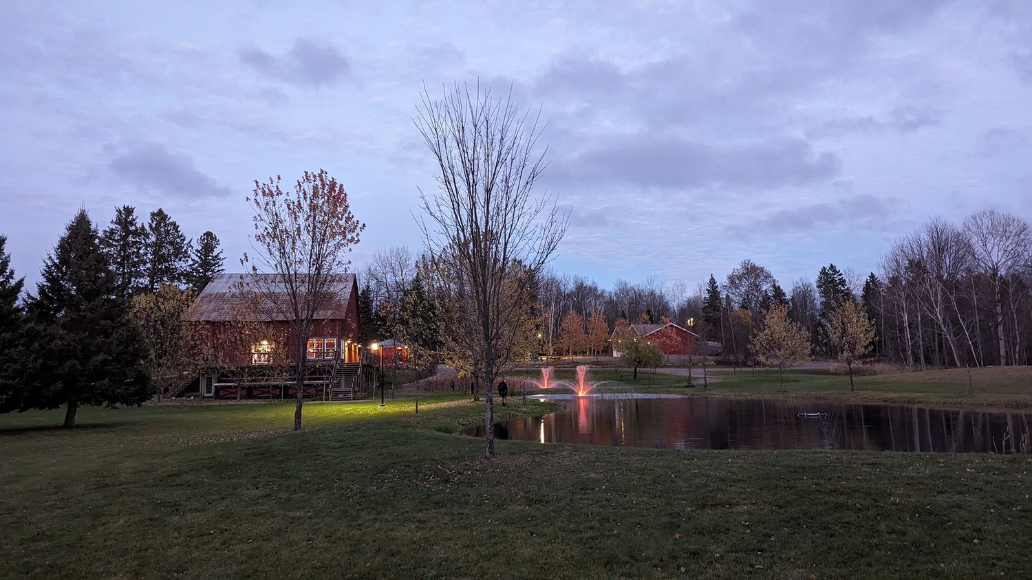 A peaceful lakeside view at dusk with buildings reflecting in the still water.
