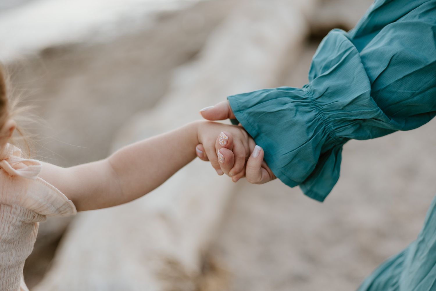 A close up image of a woman's hand holding a young child's hand.