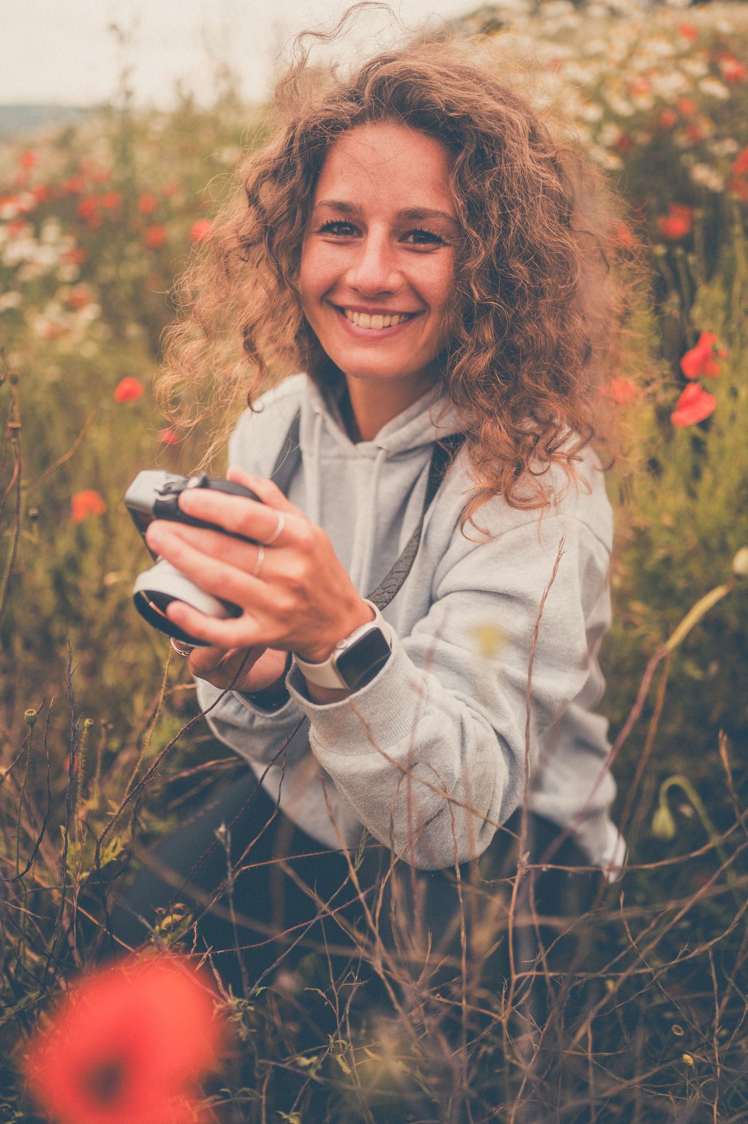 Person holding vintage camera in a wildflower meadow on a summer day.