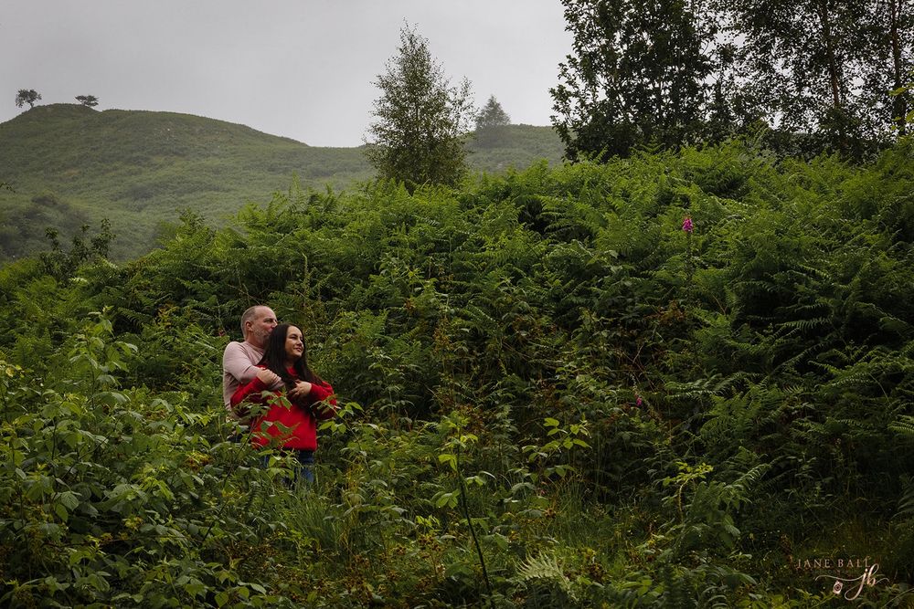 People sitting among lush green ferns on a misty hillside in nature.