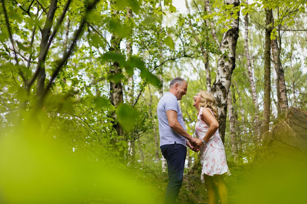A couple shares a romantic moment together surrounded by lush green foliage in an outdoor nature setting.