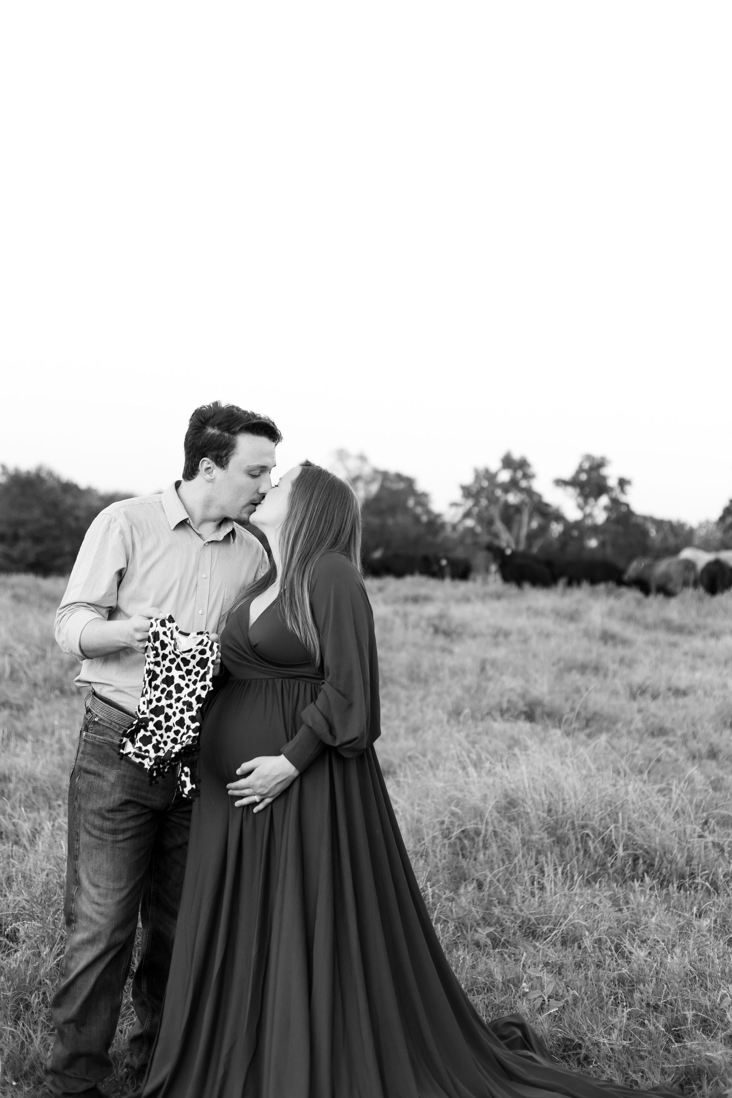 couples in love holding baby onesie, field photo in stephenville TX, black and white photo