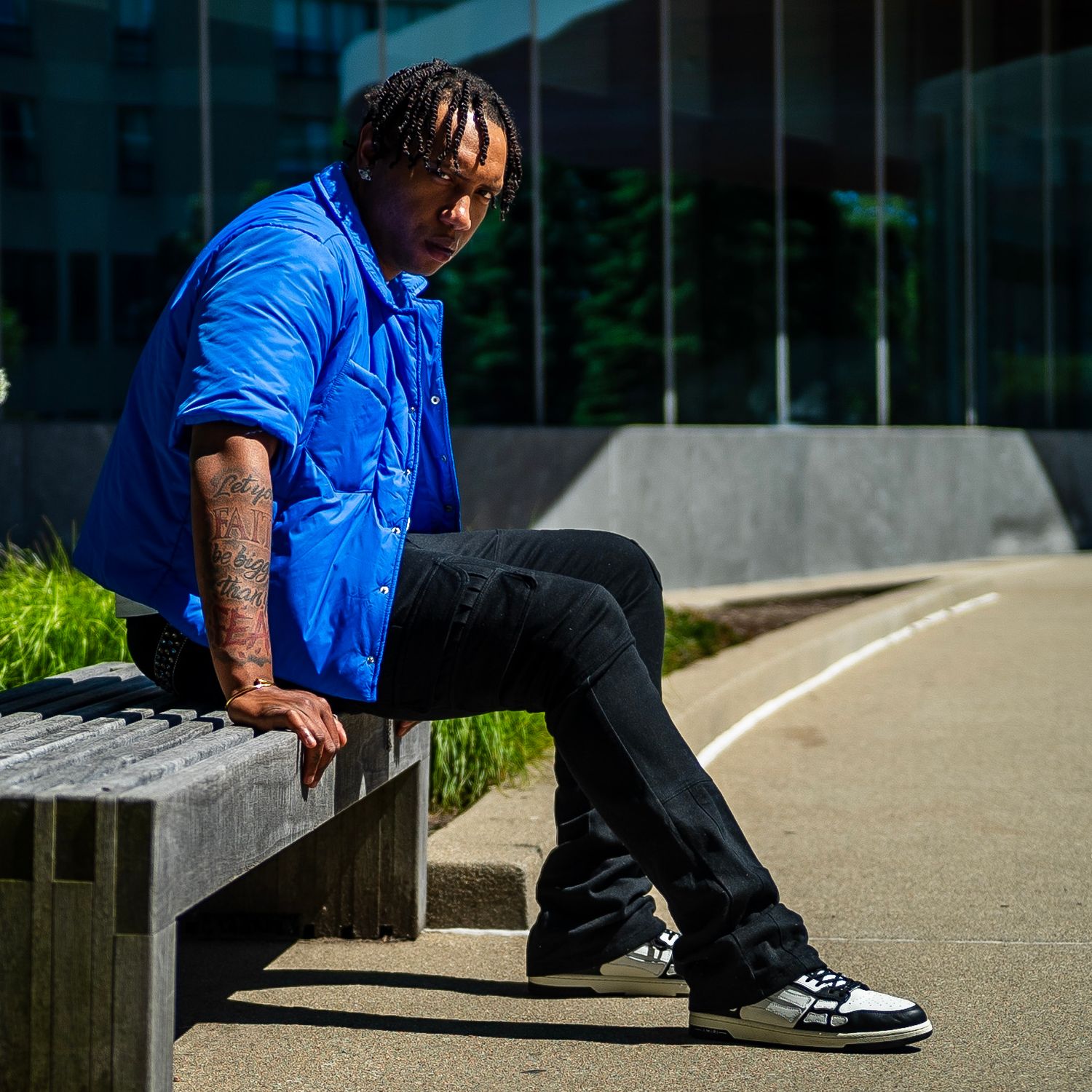 Person in blue shirt sitting on concrete steps outdoors during daytime.