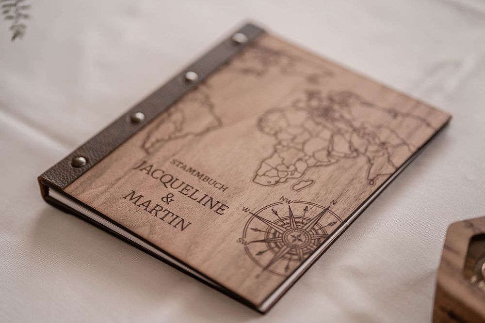 A wooden book cover displays intricate compass designs and decorative engravings burned into the natural wood surface.