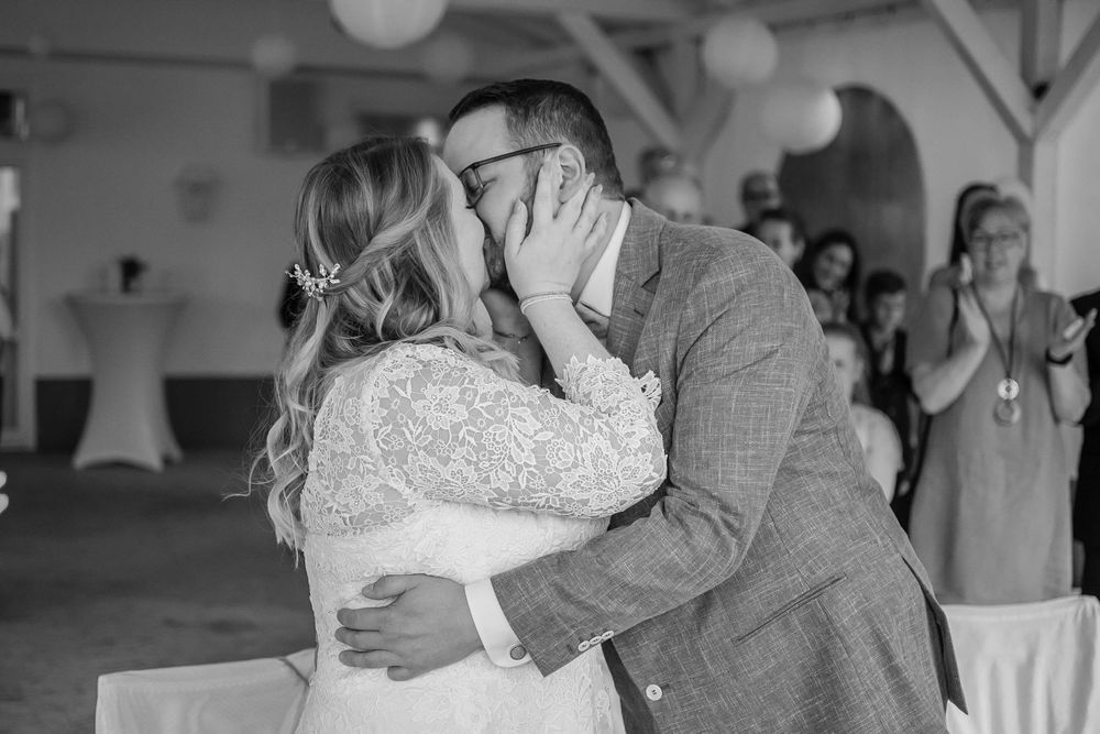 A bride and groom share a passionate kiss during their first dance at their wedding reception in a decorated venue.