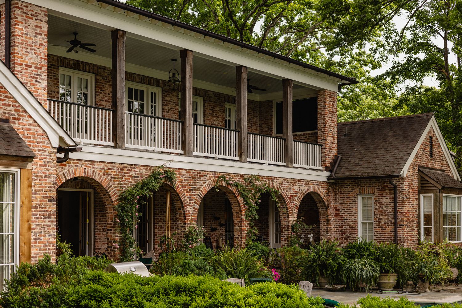 Luxurious white modern home exterior with arched walkway and brick paved driveway.