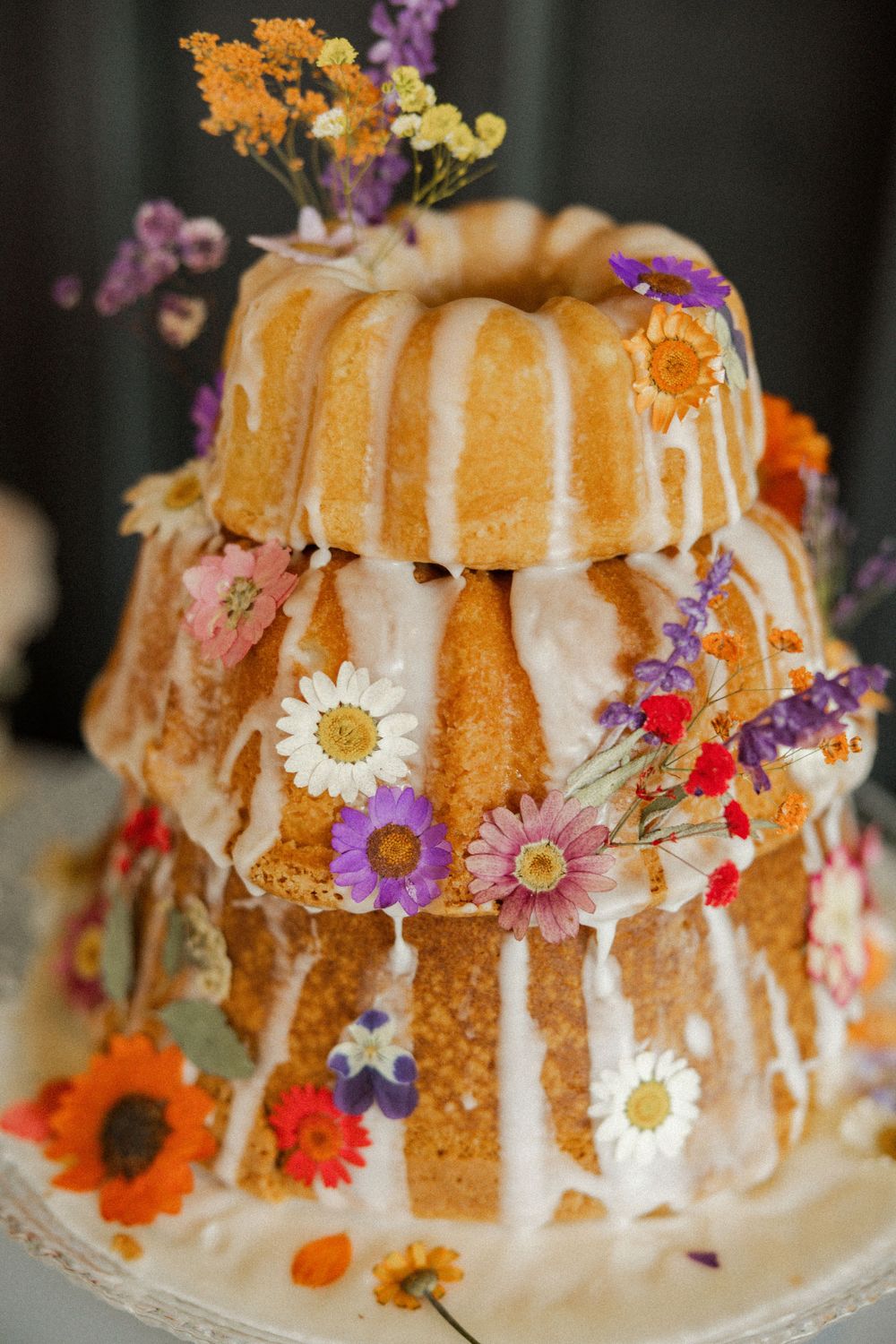 Bundt cake decorated with colorful wildflowers and white glaze dripping down the sides.