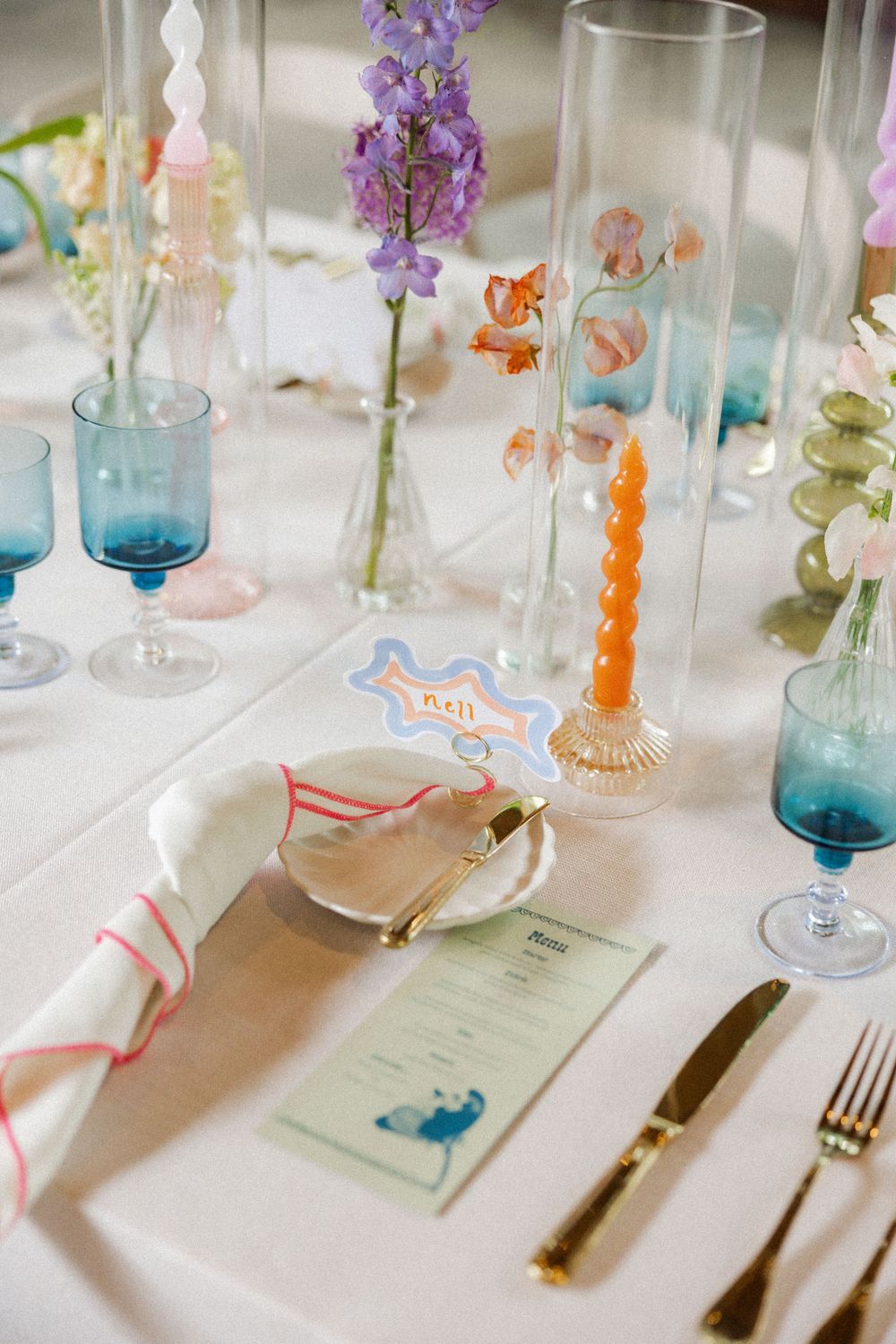 Elegant table setting with blue glassware, floral arrangements and place settings.