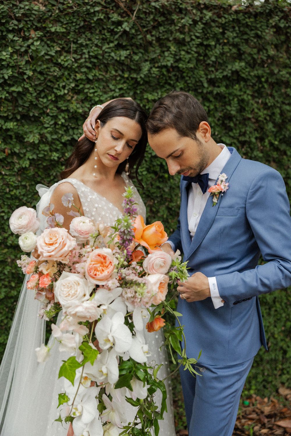 Close-up of romantic peach and white wedding bouquet with blue suit details.