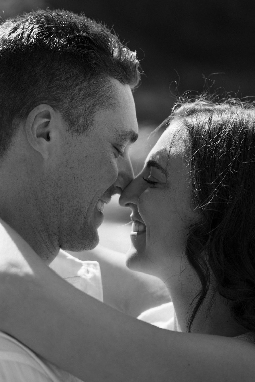 Intimate black and white close-up of couple smiling and nearly kissing outdoors. Engagement photoshoot. Victoria, BC, Vancouver Island.