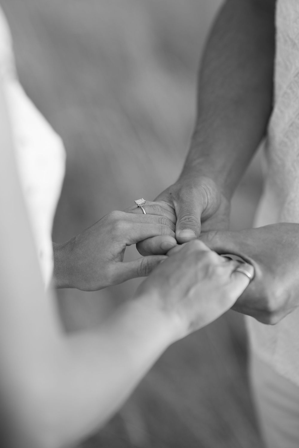 Black and white close-up of a couple exchanging a diamond engagement ring. Engagement photoshoot. Victoria, BC, Vancouver Island.