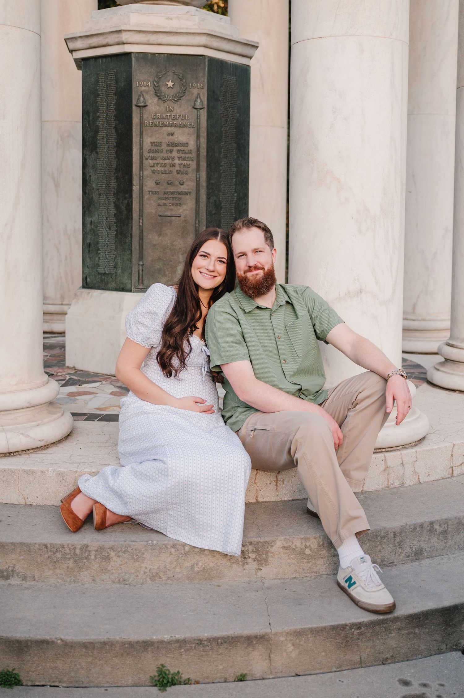 Couple seated on stone steps between classical white columns.