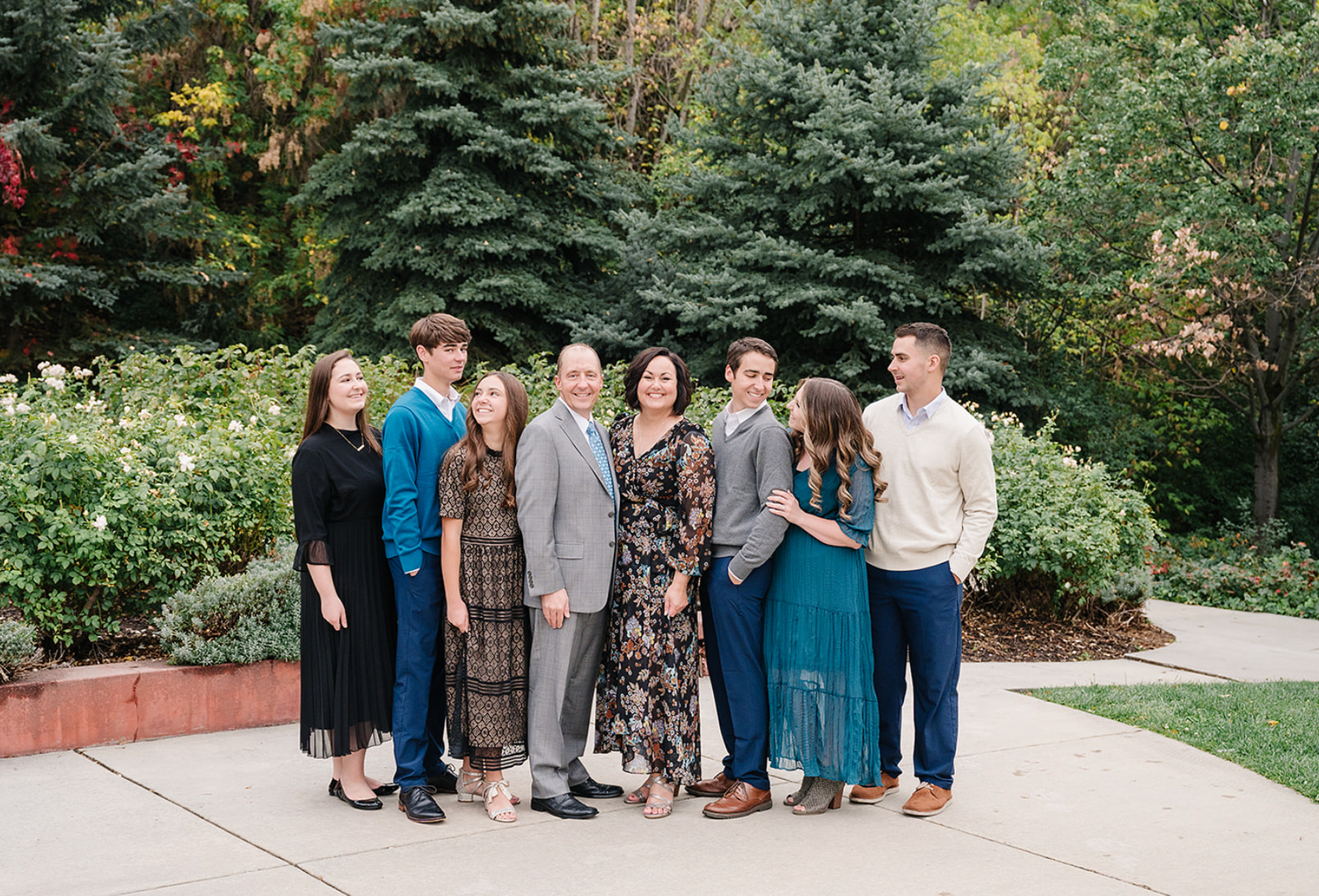Group portrait in front of evergreen trees in a garden setting wearing elegant fall attire.