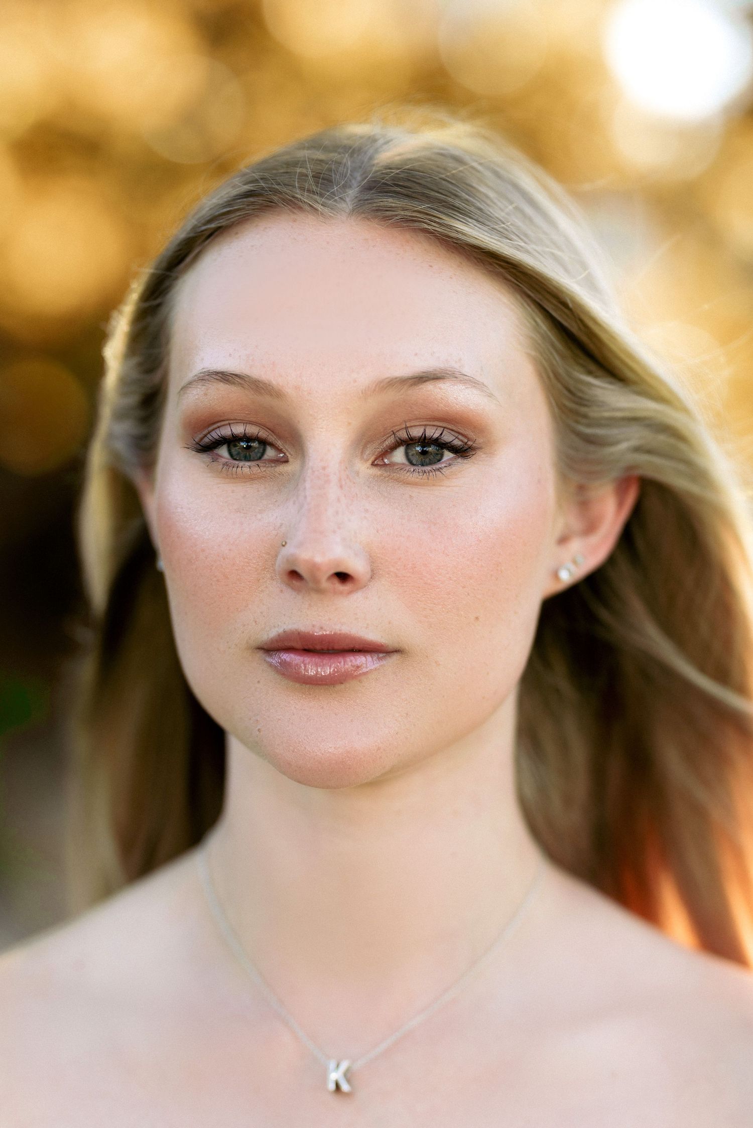 Close-up beauty portrait with natural makeup and delicate necklace.