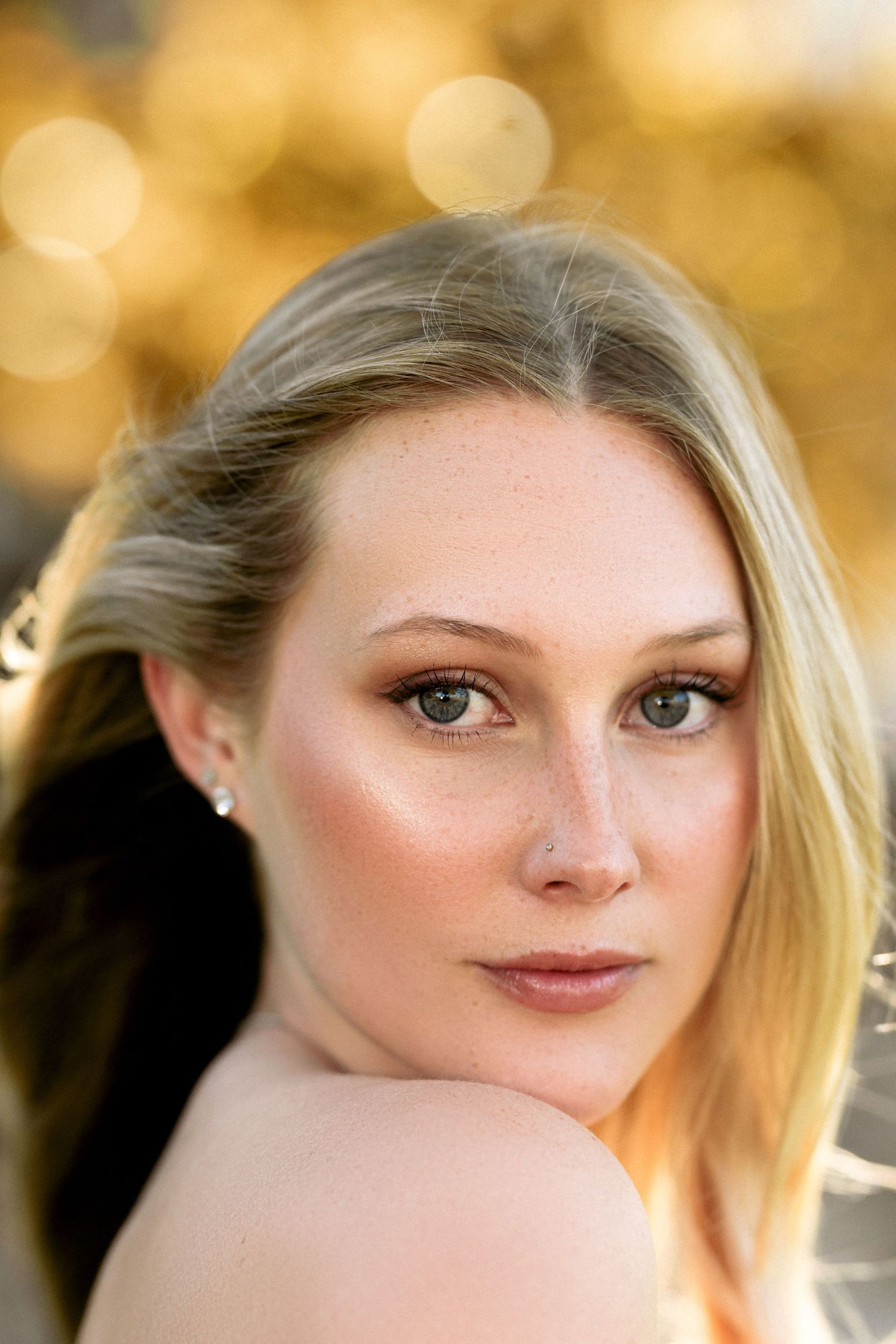 Portrait with soft golden bokeh background and natural makeup look.