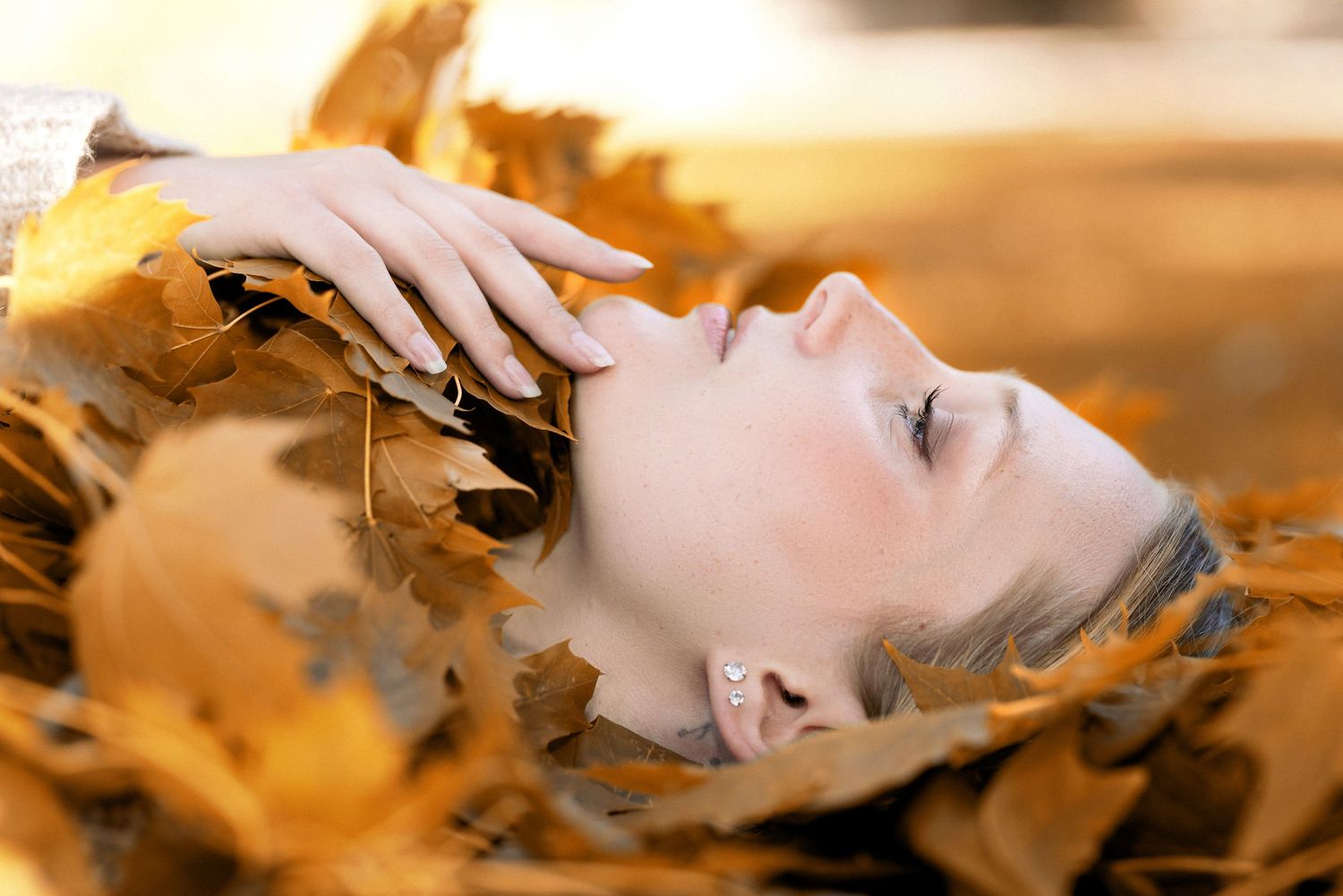 Artistic portrait lying among golden autumn leaves.