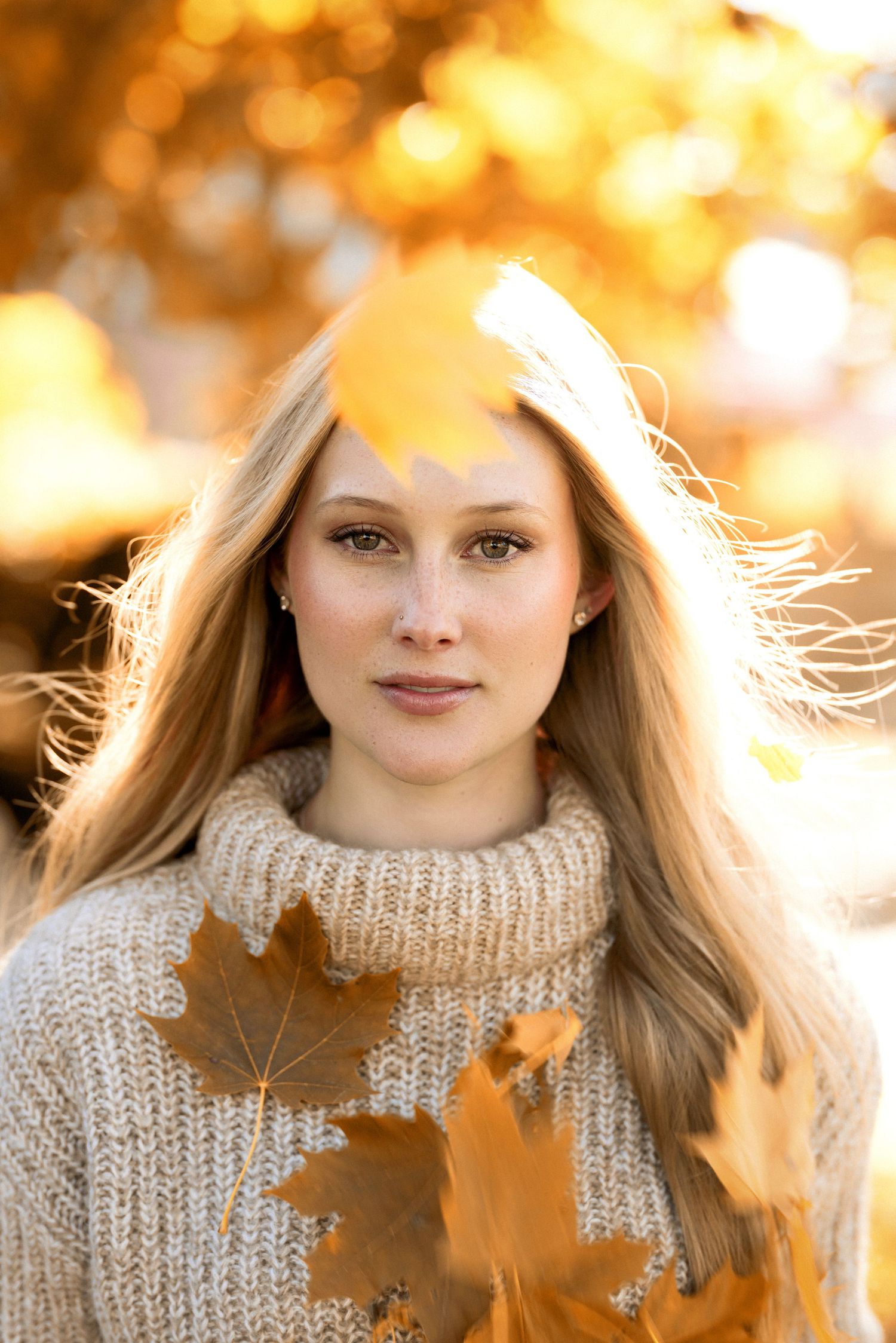 Autumn portrait in knit sweater with golden leaves and bokeh lighting effects.