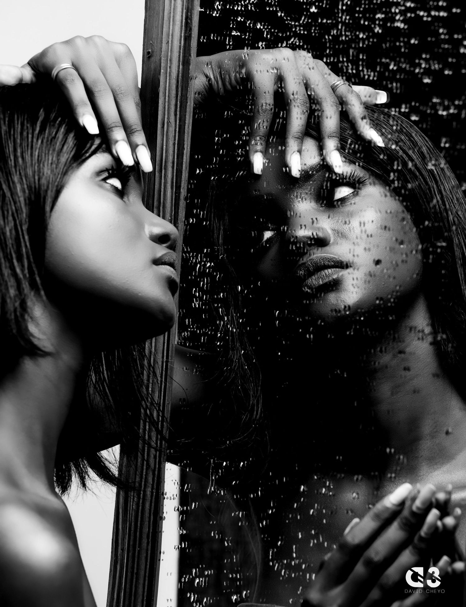 Moody black and white portraits through water-streaked glass creating artistic effect.