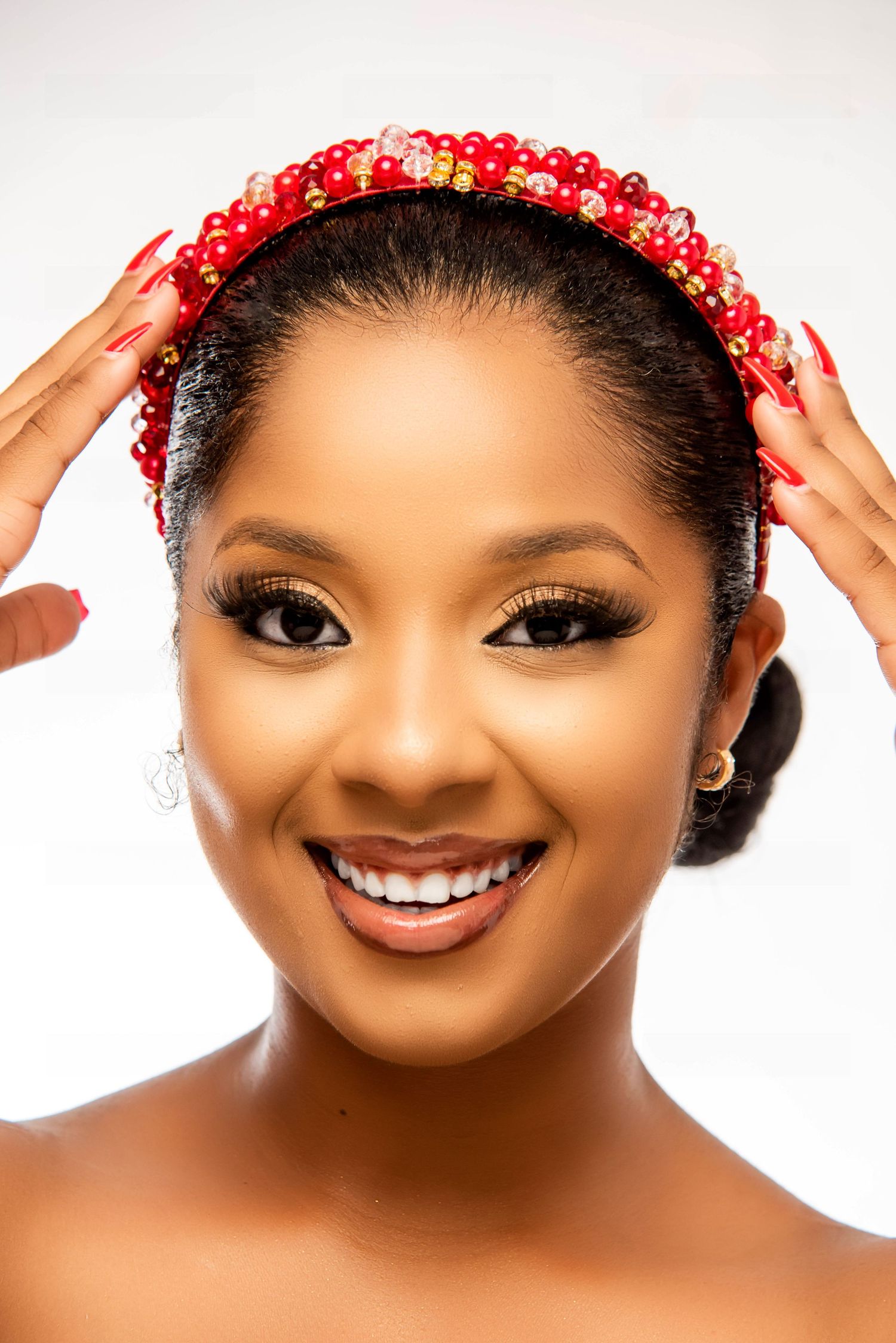 Portrait of a radiant smile adorned with a decorative red beaded headpiece and glamorous makeup.