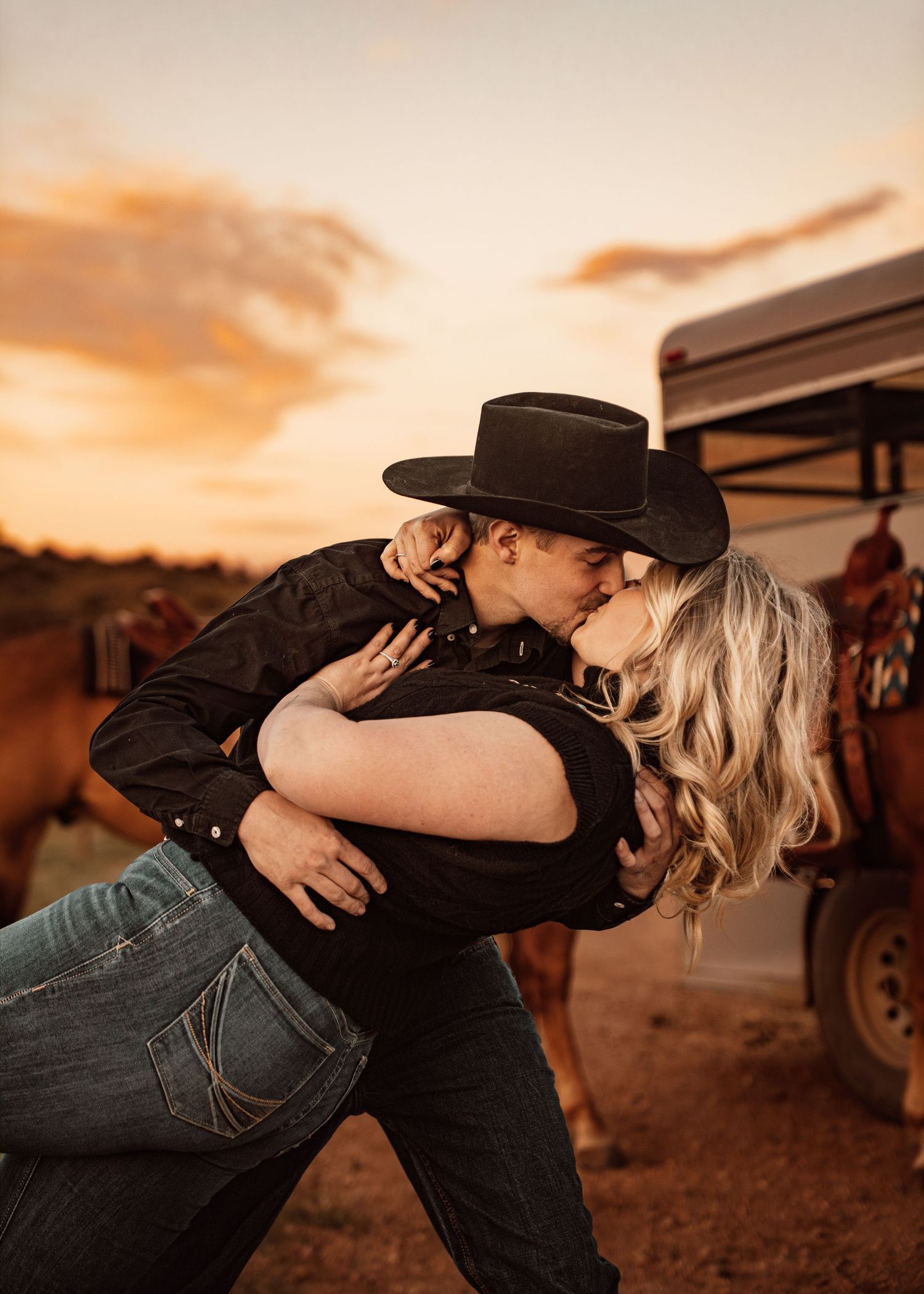A couple shares an intimate embrace against a forested background in warm sepia tones.