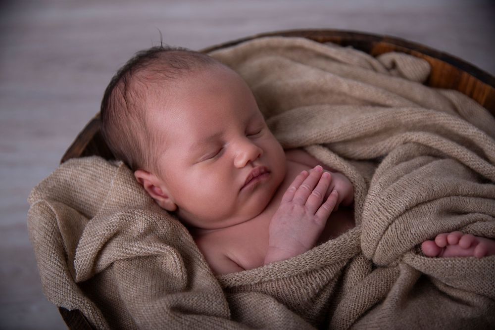 Newborn photographer Gold Coast safely posing baby in neutral wrap.