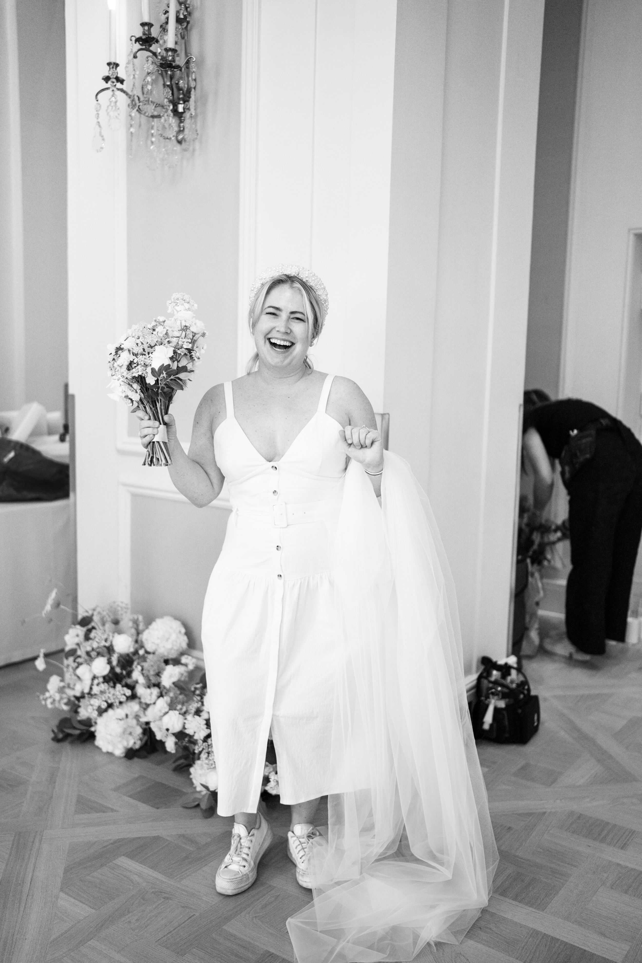 Wedding preparation scene in bright interior with flowing white dress and sneakers.