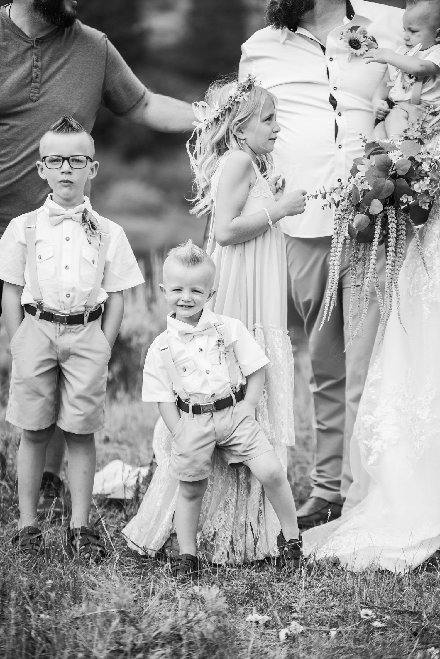 Black and white photo of children dressed up at a formal outdoor wedding gathering.