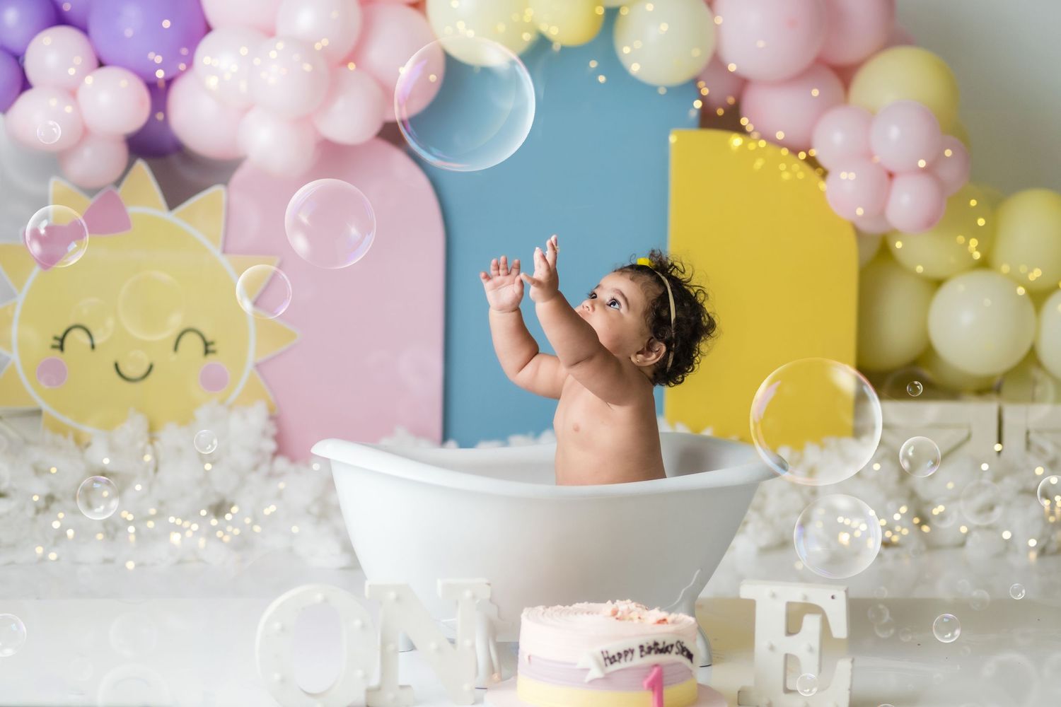 Whimsical birthday scene with pastel balloon arch and floral accents in purple and peach tones.