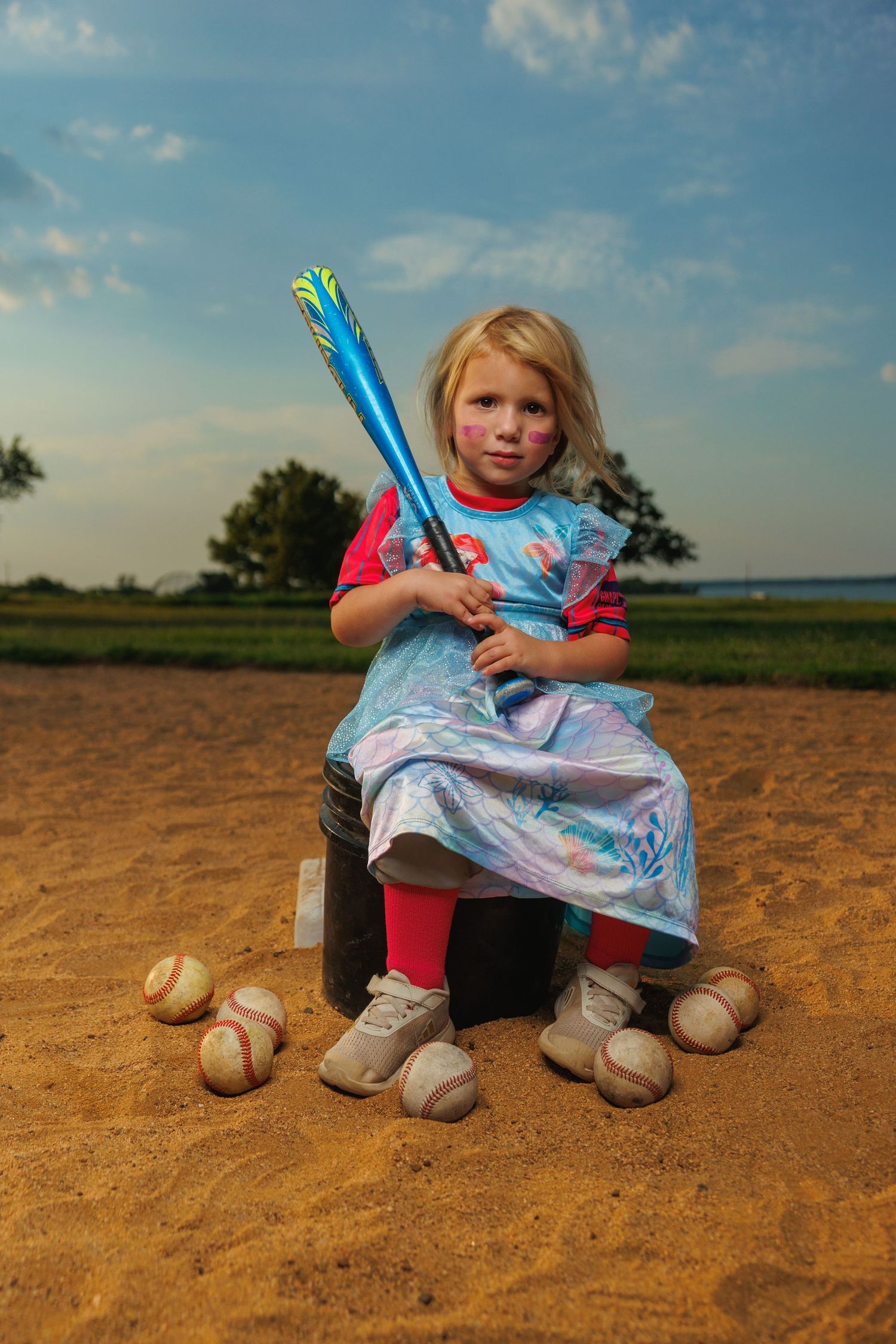 Softball player leaps with glove and ball against blue sky backdrop.