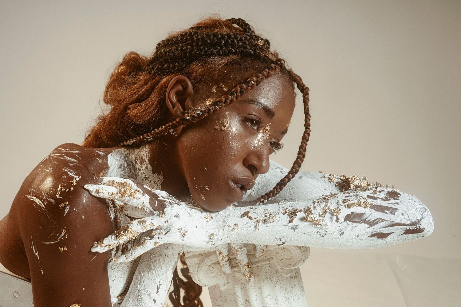 Creative portrait with white paint splash effect and intricate braided hairstyle.