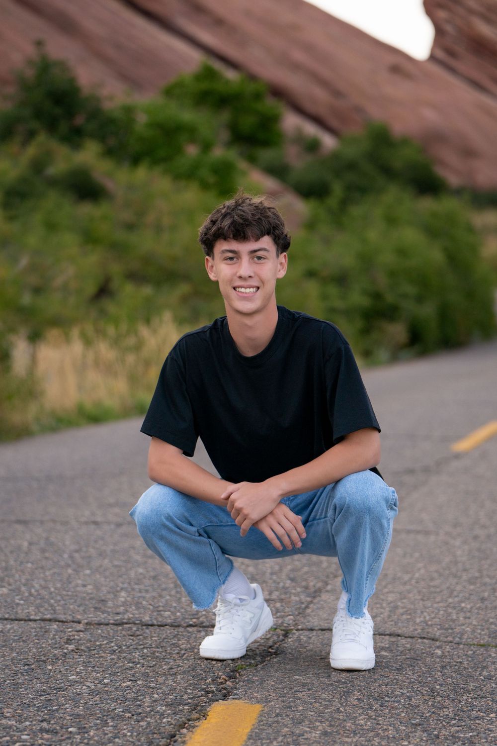 A casual portrait on a paved road with red rocks in the background. High school senior.