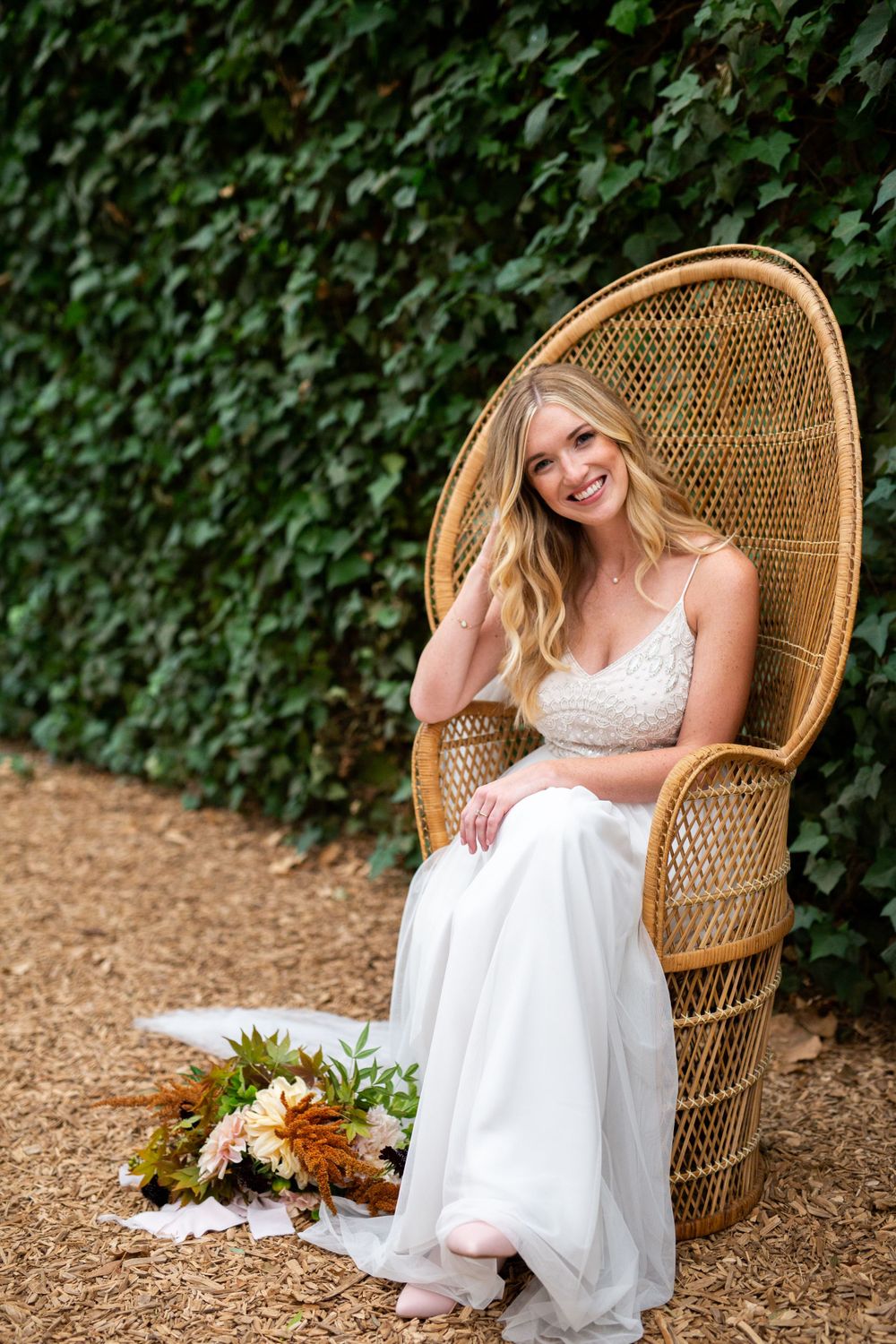 Peacock chair with ivy wall backdrop creates bohemian wedding scene.