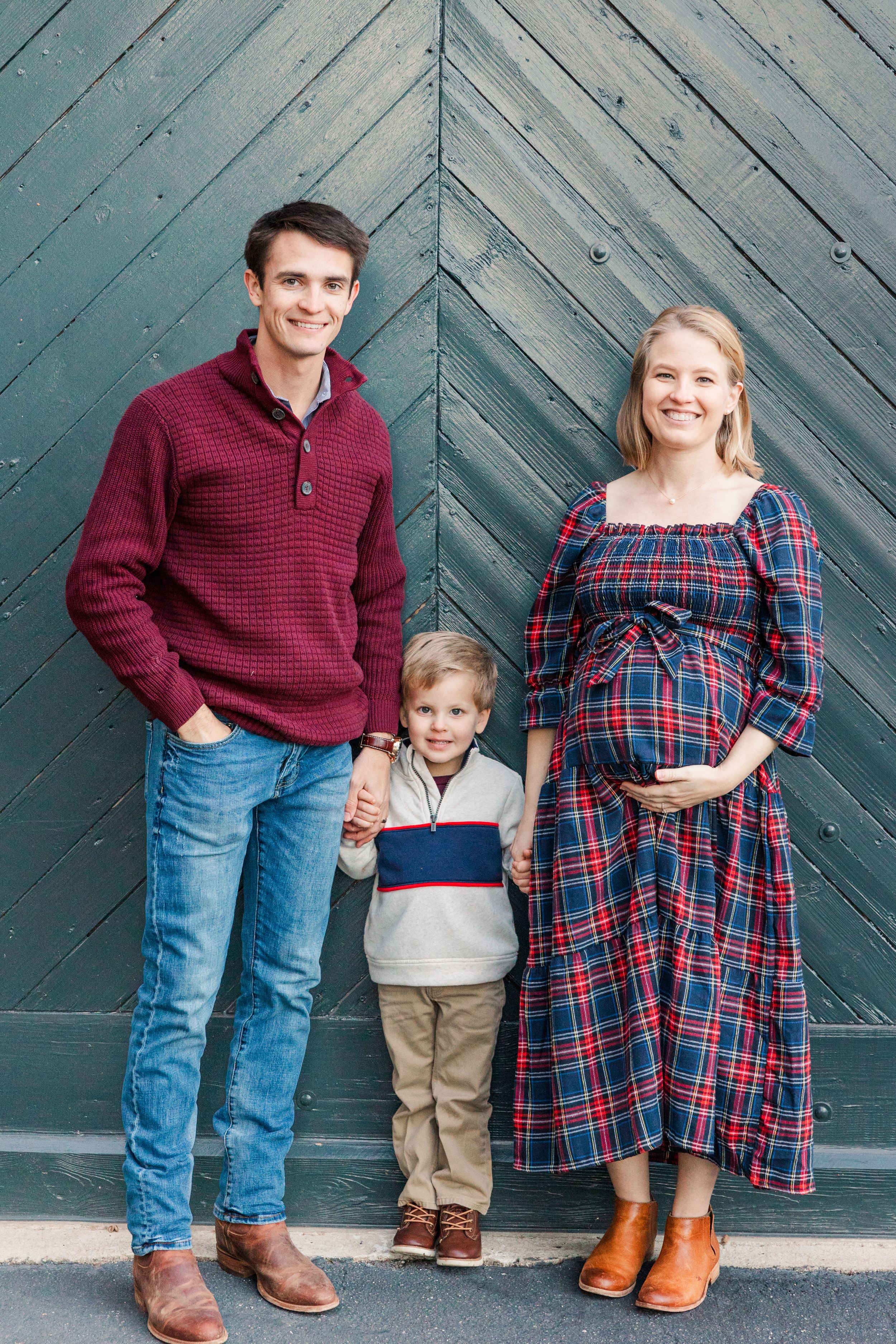 Family poses against blue chevron door during maternity photo session.
