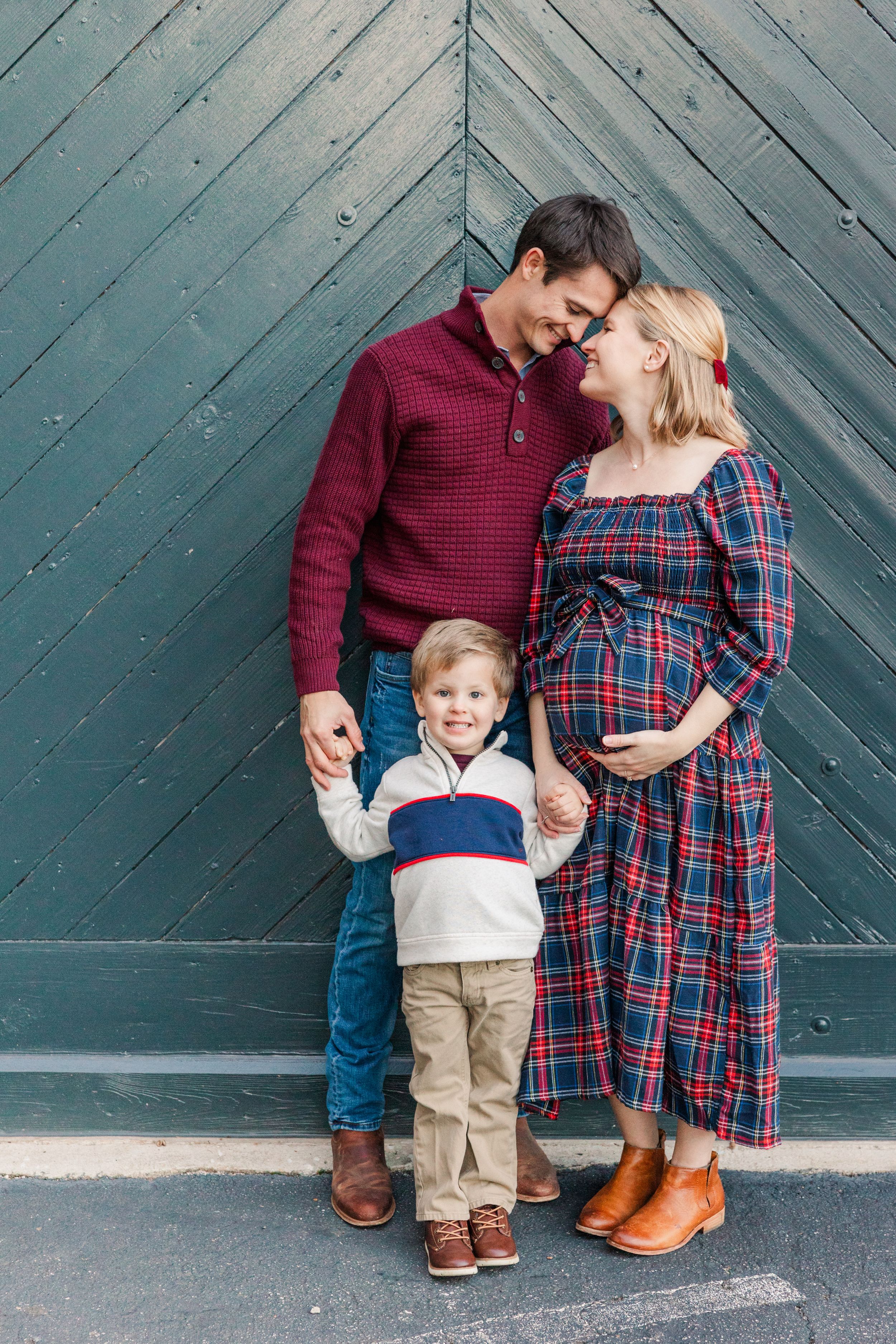 Loving family portrait against blue wooden door during pregnancy photoshoot.